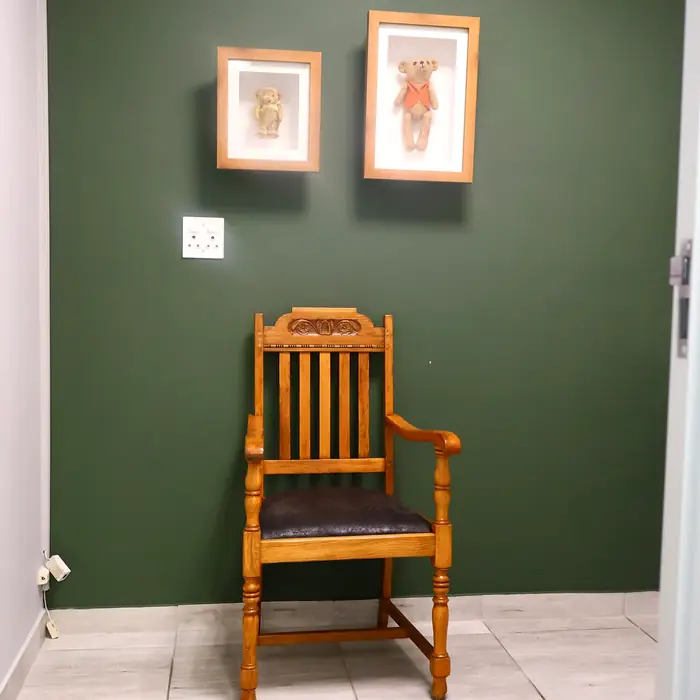 Framed vintage teddy bears on the wall above a wooden chair